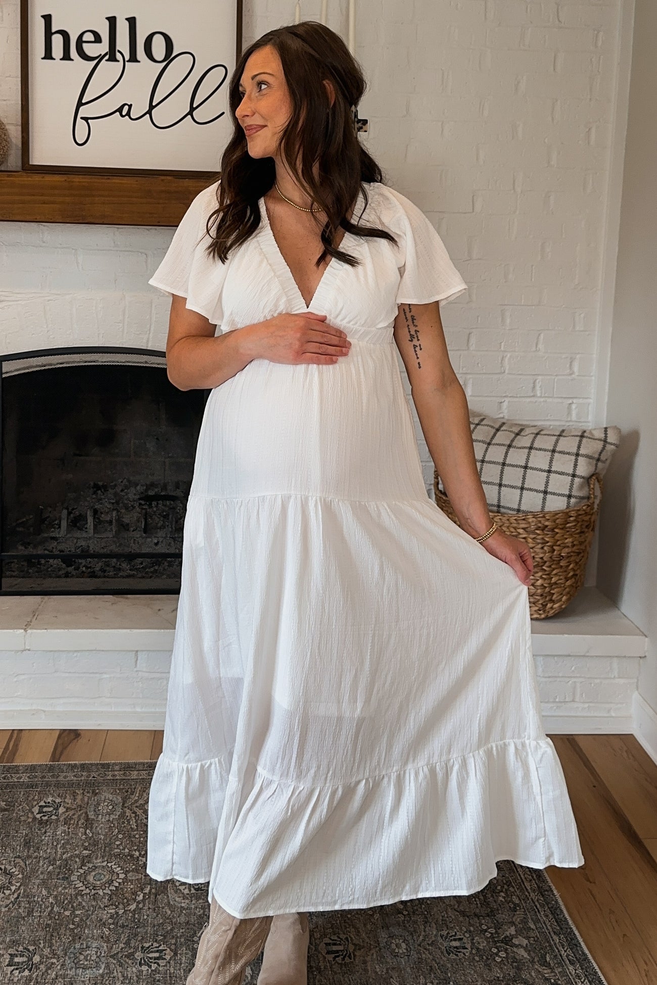 woman wearing a white short sleeve maternity maxi dress and showing her baby bump