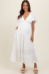 woman wearing a white maternity maxi dress with flutter sleeves and a baby bump visible