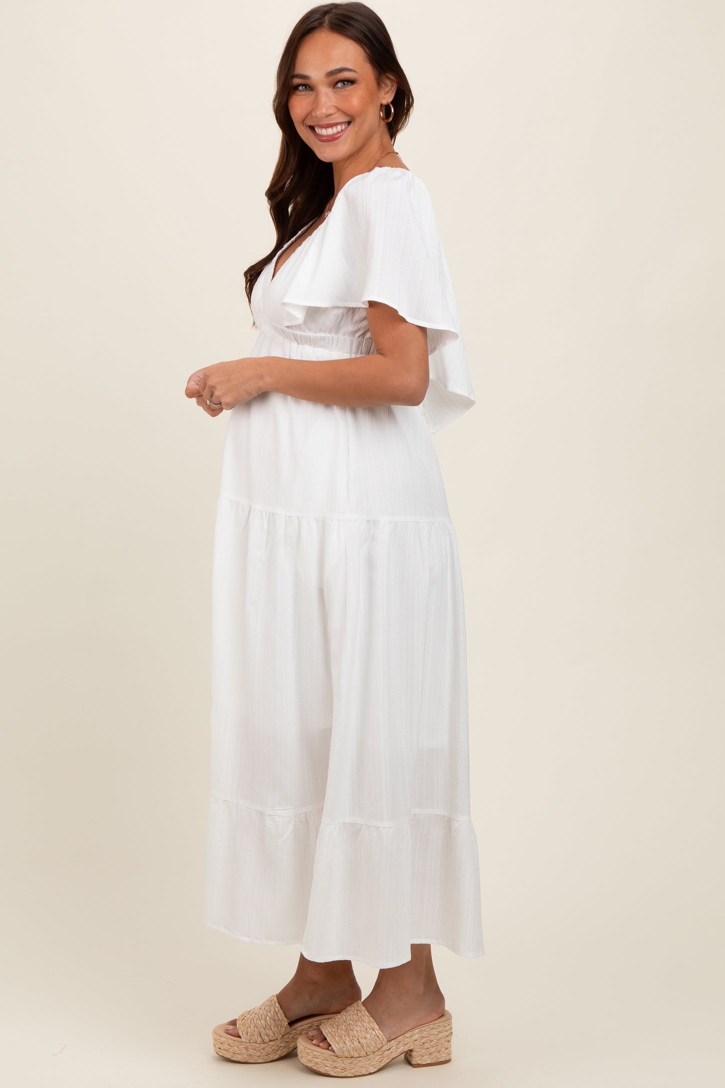 woman wearing a white tiered maternity dress with flutter sleeves and a baby bump visible
