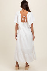 woman wearing a white maternity maxi dress with flutter sleeves and an open back design