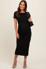 woman wearing a black short sleeve maternity dress with a ruched design and a baby bump, holding a handbag