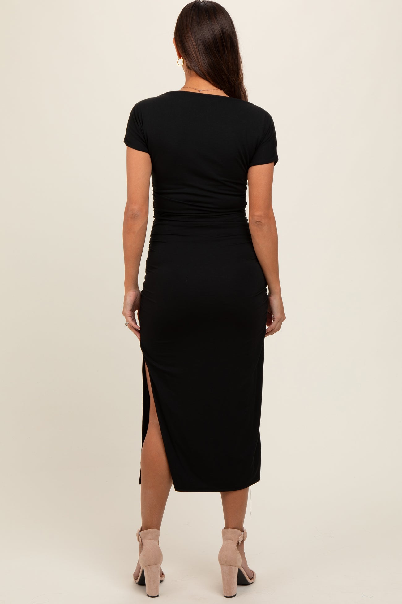 woman wearing a black short sleeve maternity maxi dress with a side slit, showing a smooth silhouette from the back
