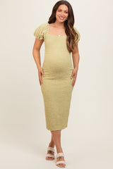 woman wearing a light green short sleeve maternity dress with a fitted silhouette and puffed sleeves, showing her baby bump