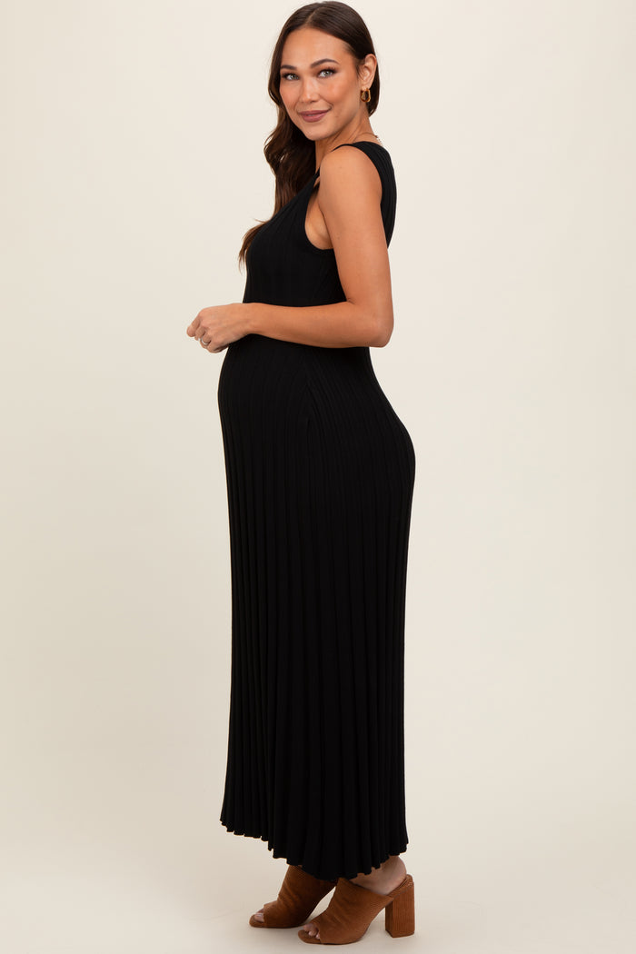 woman wearing a black ribbed maternity maxi dress, showing her baby bump and smiling to the side
