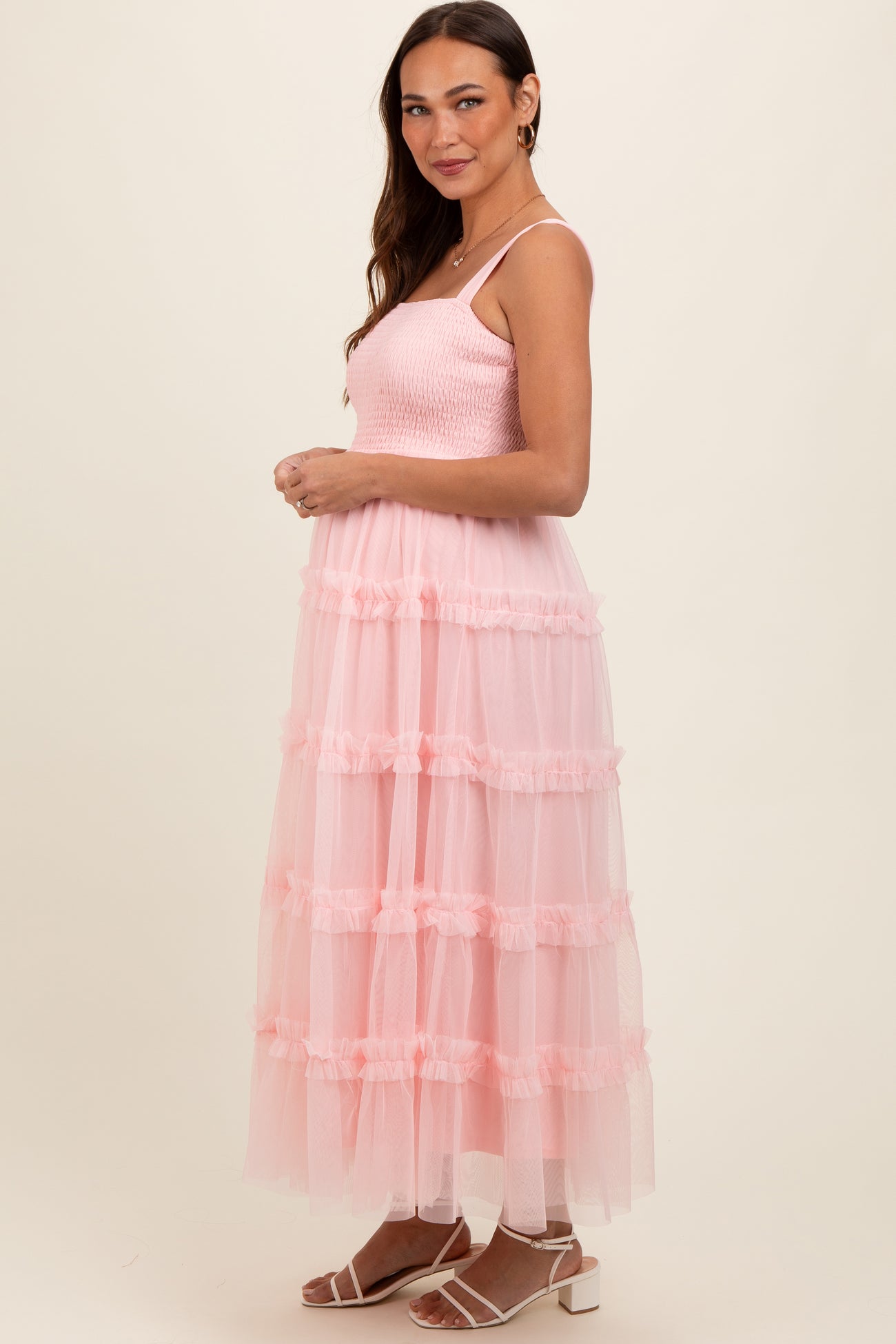 woman wearing a pink tiered tulle maternity dress with a smocked bodice and spaghetti straps