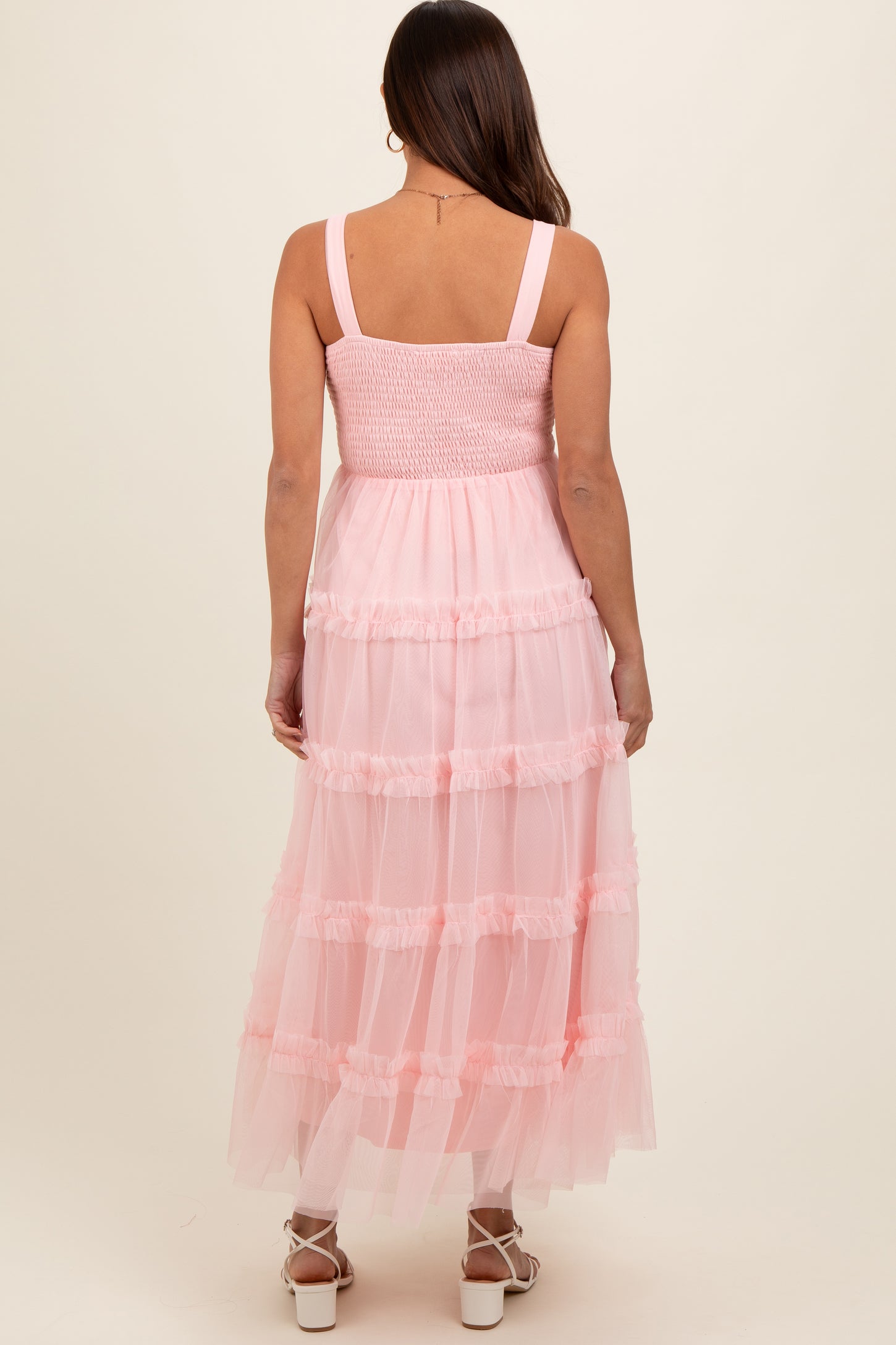 woman wearing a pink maternity dress with a smocked bodice and tiered tulle skirt