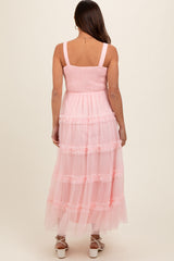 woman wearing a pink maternity dress with a smocked bodice and tiered tulle skirt