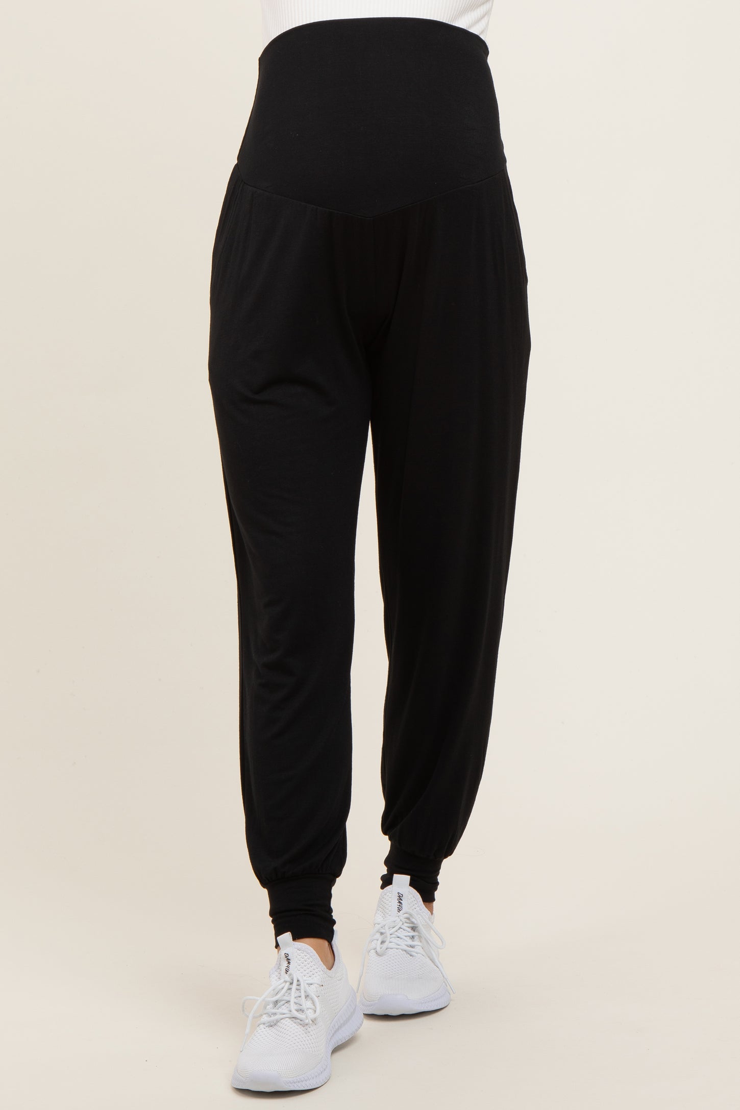woman wearing black maternity jogger pants with a high waistband and side pockets, paired with white sneakers