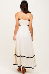 woman wearing a white maxi dress with black trim and spaghetti straps, shown from the back
