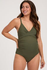 woman wearing an olive green maternity swimsuit with a v-neck and side ruching, showing her baby bump