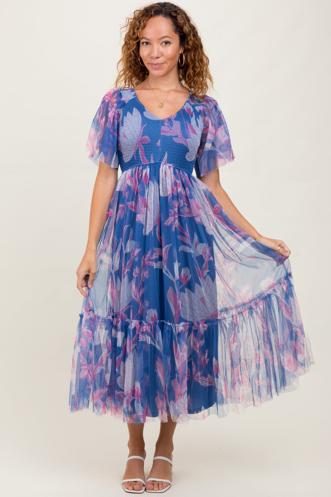 woman wearing a blue floral midi dress with puff sleeves and a tiered tulle skirt