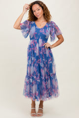 woman wearing a blue floral tulle maxi dress with puff sleeves and a tiered hem