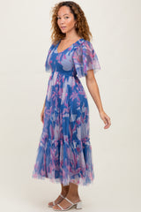 woman wearing a blue floral print maxi dress with flutter sleeves and a ruffled hem
