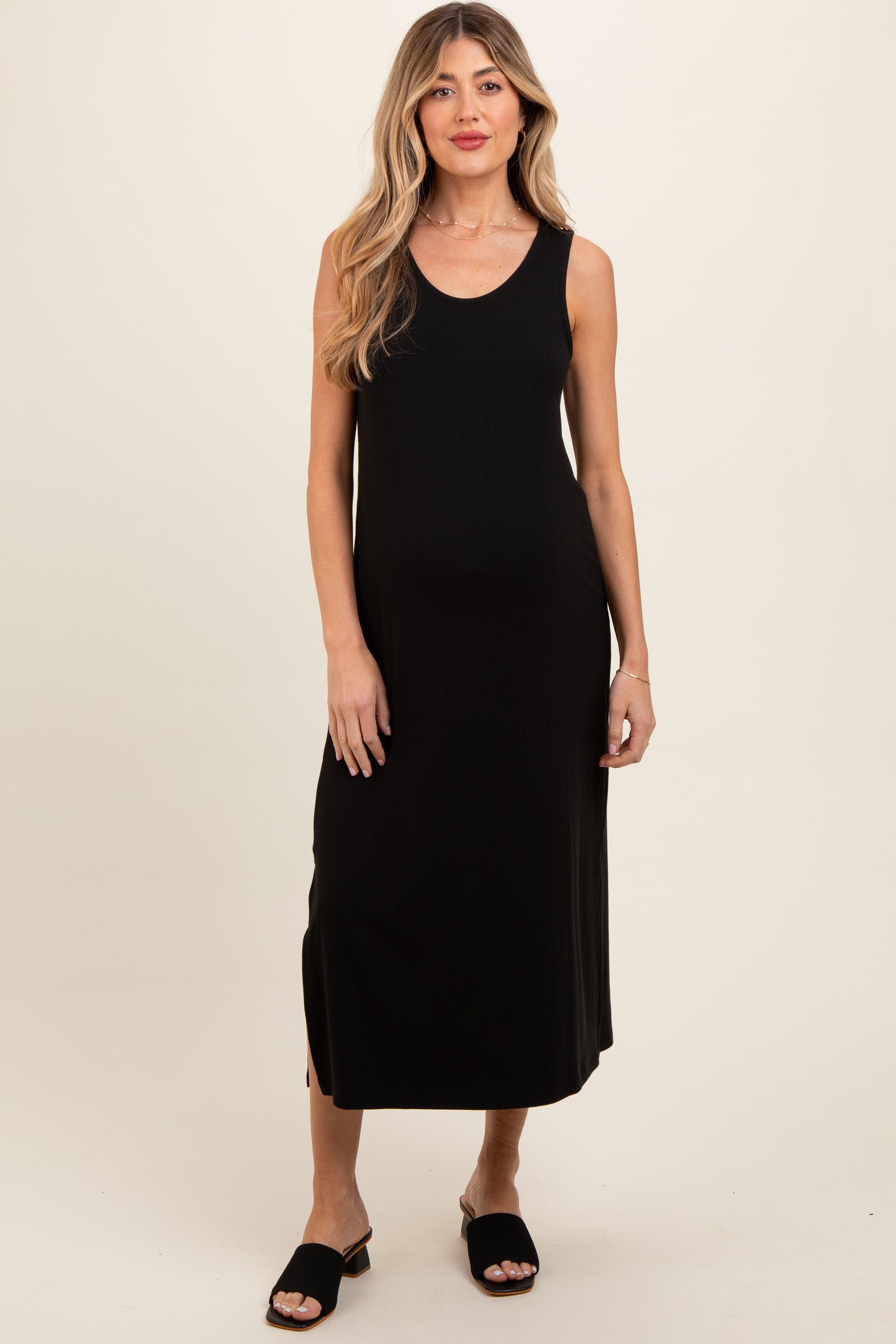 woman wearing a black sleeveless maxi maternity dress with a side slit and showing her baby bump
