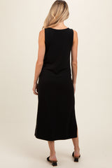 woman wearing a black sleeveless ribbed maternity dress with a side slit, showcasing her back