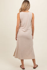 woman wearing a beige sleeveless maternity maxi dress with a side slit