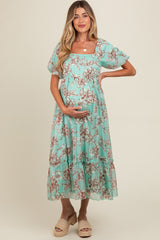 woman wearing a mint green floral maternity dress and holding her baby bump