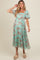 woman wearing a mint green floral maternity dress with short sleeves and a tiered skirt, showing her baby bump