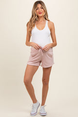 woman wearing a white tank top and pink maternity shorts with a drawstring, showing off her baby bump