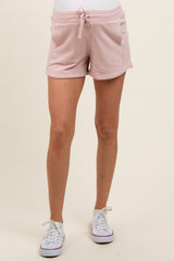 woman wearing light pink maternity shorts with a drawstring waist and side pockets