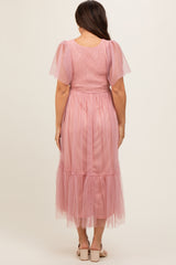 woman wearing a pink maternity dress with tulle puff sleeves and a flowing skirt, showing the back view