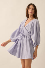 woman wearing a light lavender puff sleeve mini dress with a v-neck and gathered waist
