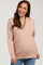 woman wearing a light pink maternity pullover with a half zip and ribbed fabric, smiling and showing her baby bump