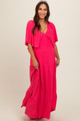 woman wearing a bright pink maternity maxi dress with a matching lightweight cardigan and a visible baby bump