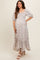 woman wearing a floral print maternity maxi dress with puff sleeves and a smocked bodice, showcasing her baby bump