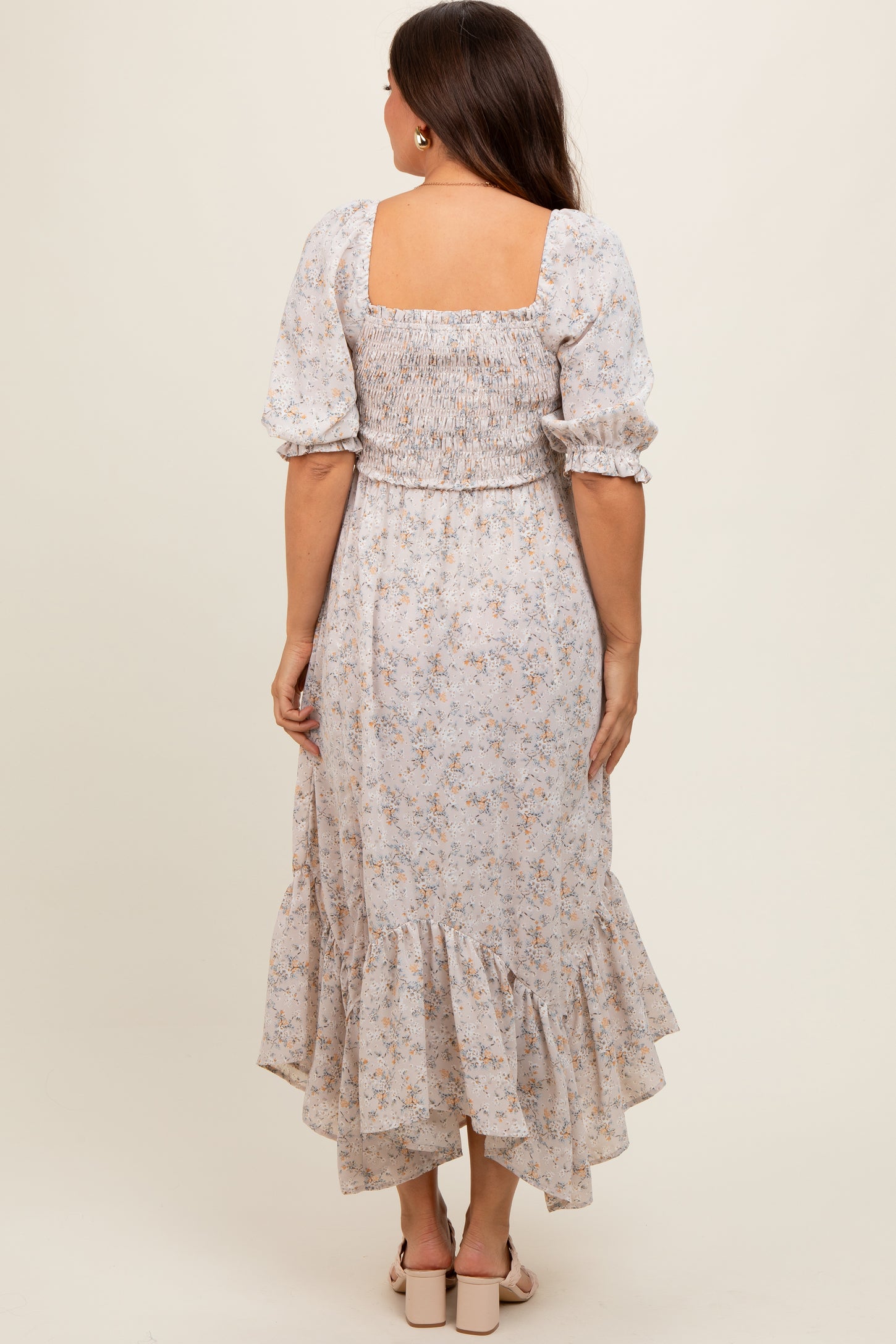 woman wearing a floral maternity maxi dress with a smocked back and ruffled hem, showing a baby bump