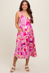 woman wearing a pink patterned maternity dress with pockets, showcasing her baby bump