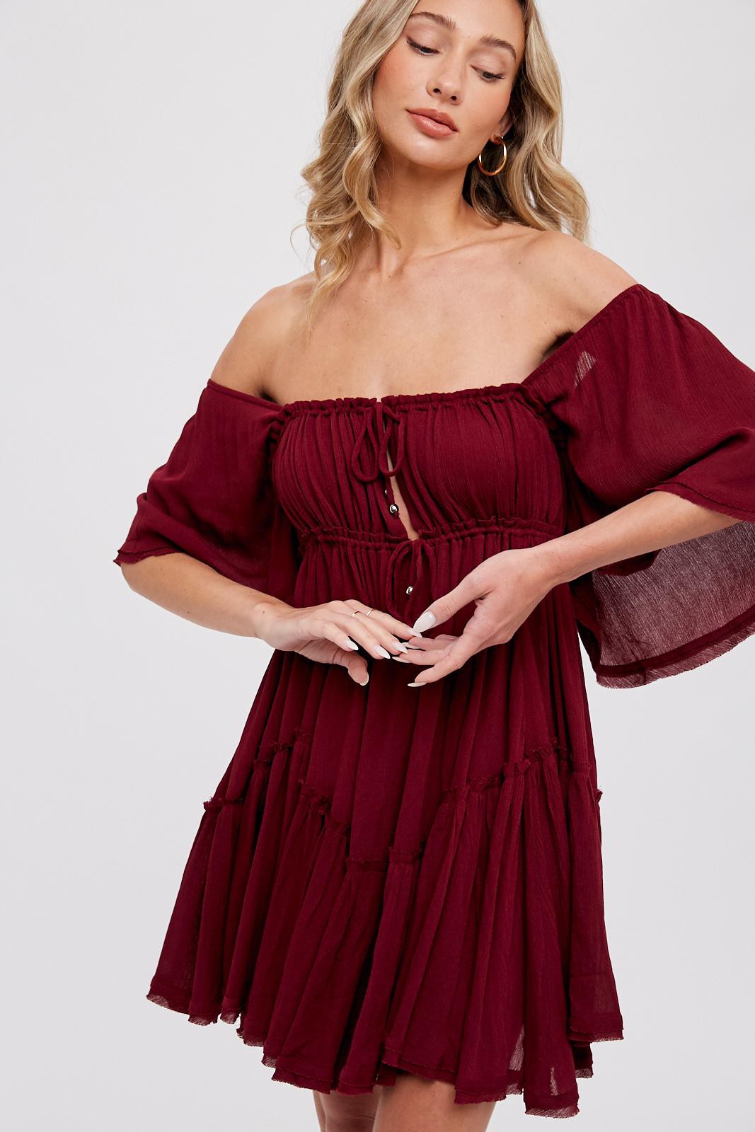woman wearing a burgundy off-shoulder dress with ruffled sleeves and a button-up front