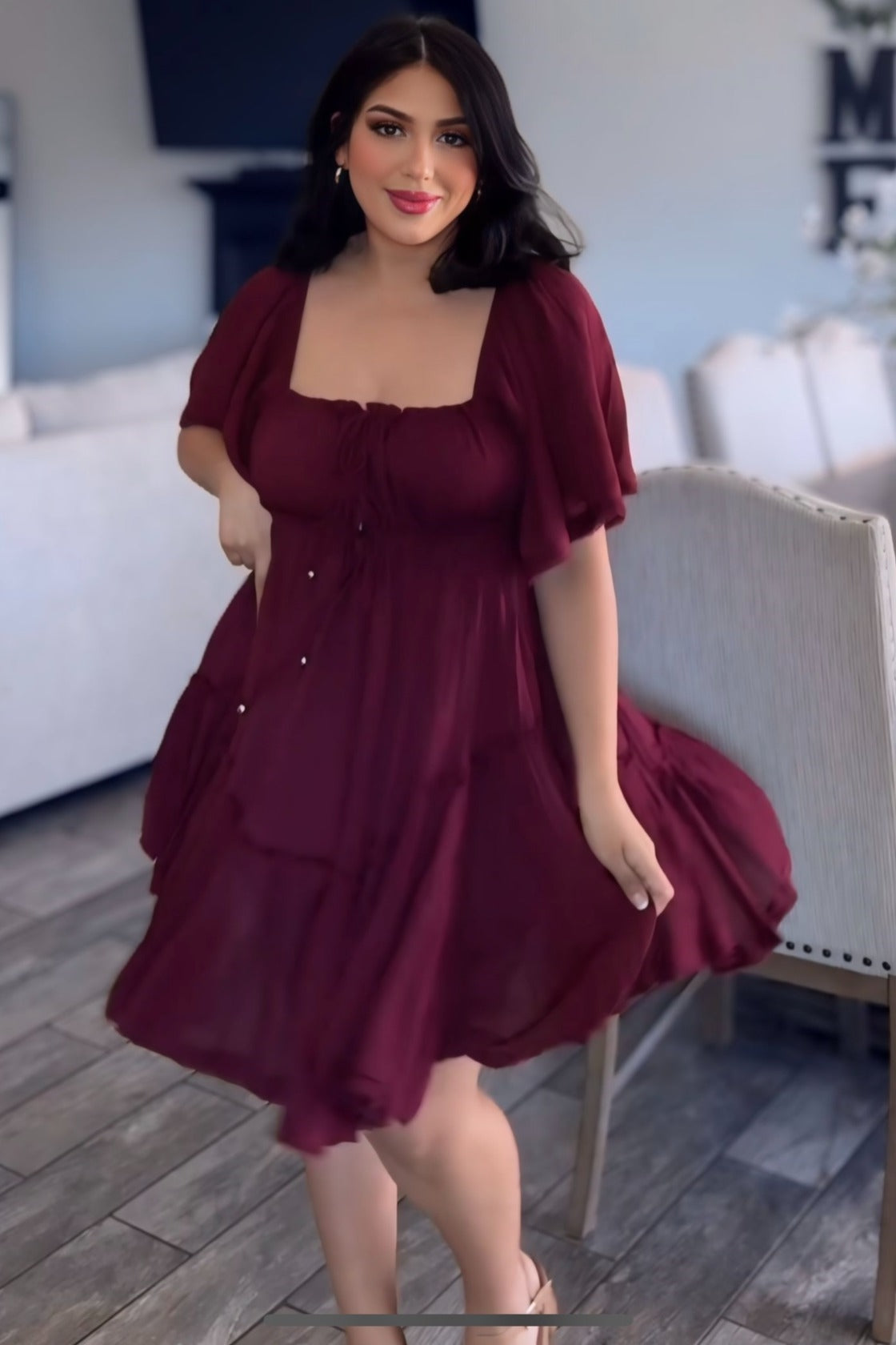 woman wearing a burgundy short sleeve dress with a gathered waist and a flowing skirt