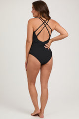 woman wearing a black maternity one-piece swimsuit with crisscross straps and a high cut leg design