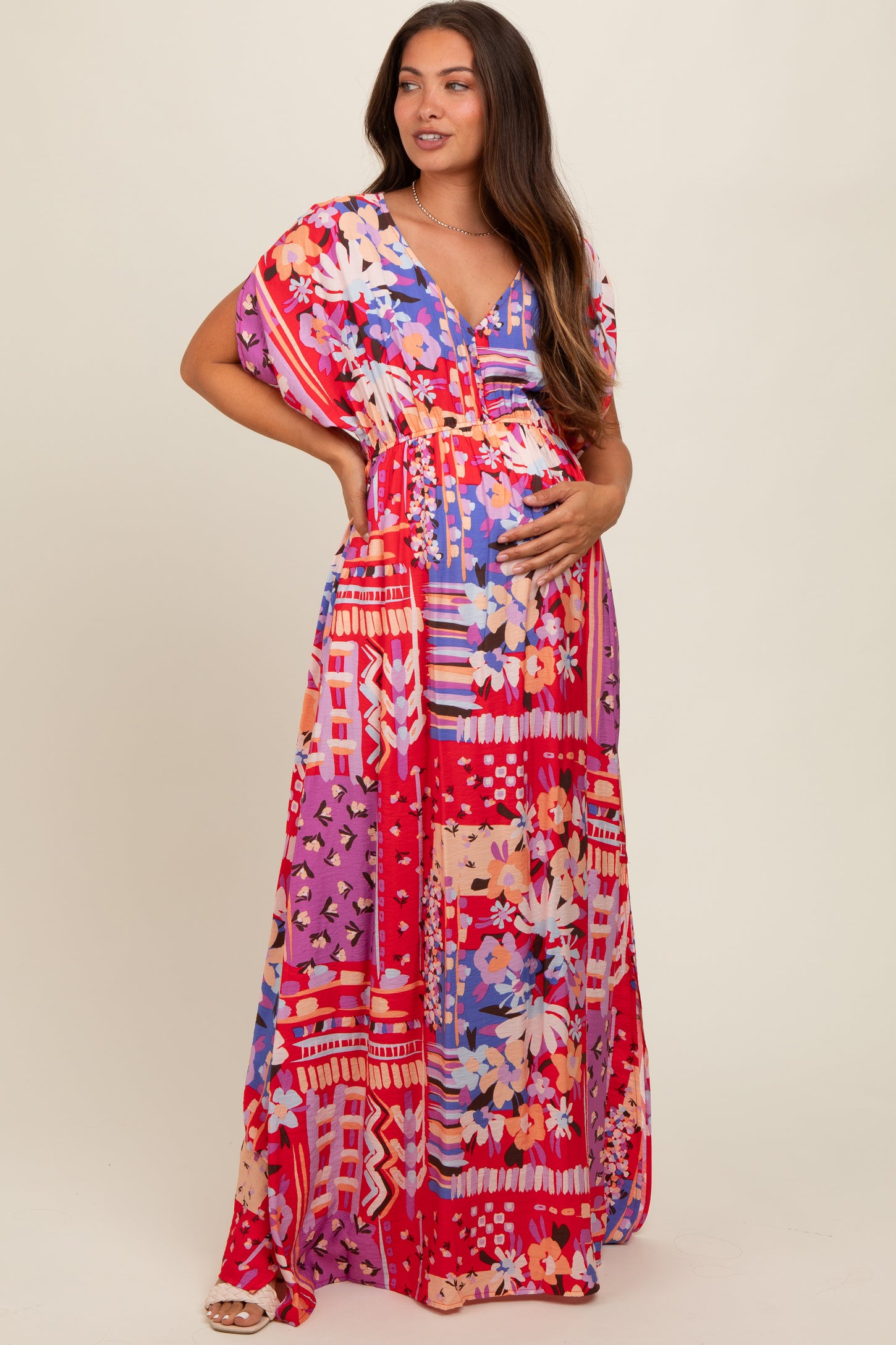 woman wearing a vibrant floral maternity maxi dress with short sleeves and a v-neck, showcasing her baby bump