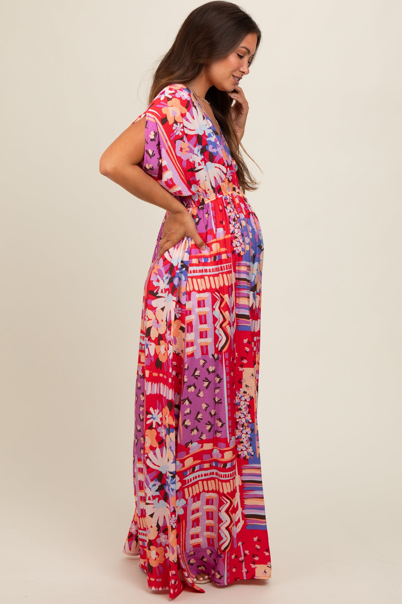 woman wearing a vibrant floral print maternity maxi dress with short sleeves and a baby bump visible