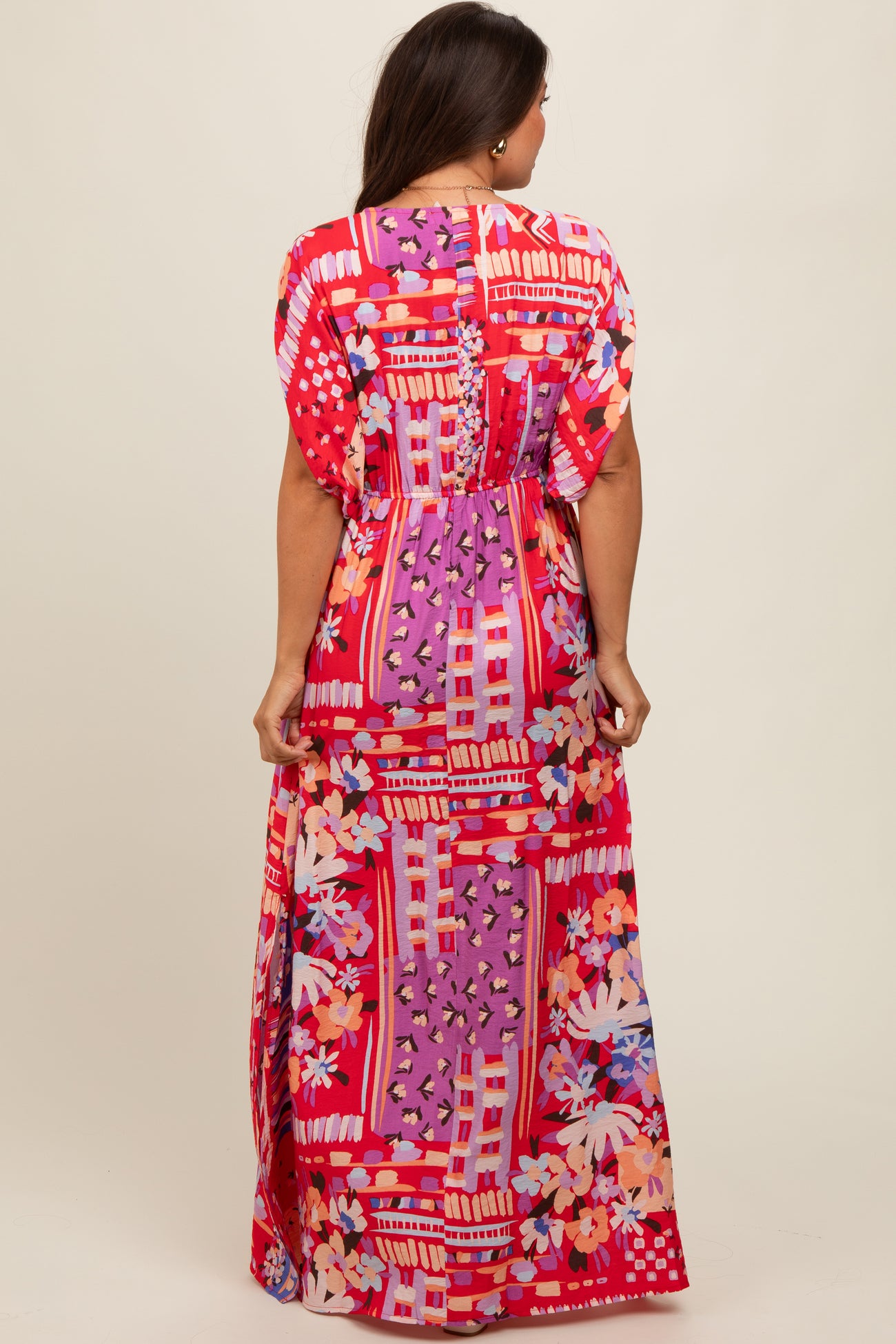 woman wearing a colorful maxi maternity dress with floral and geometric patterns, showing the back view