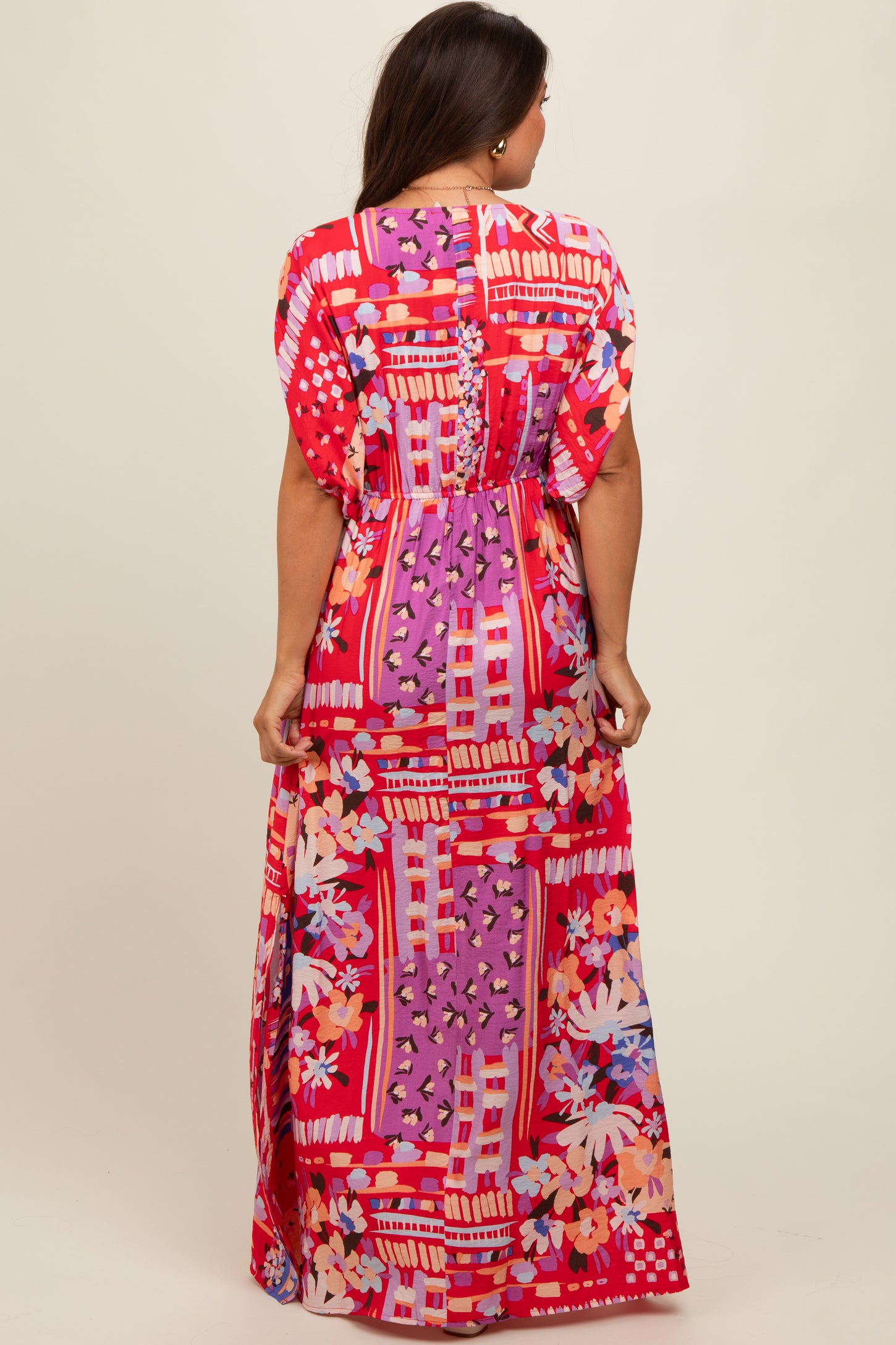 woman wearing a colorful maxi maternity dress with floral and geometric patterns, showing the back view