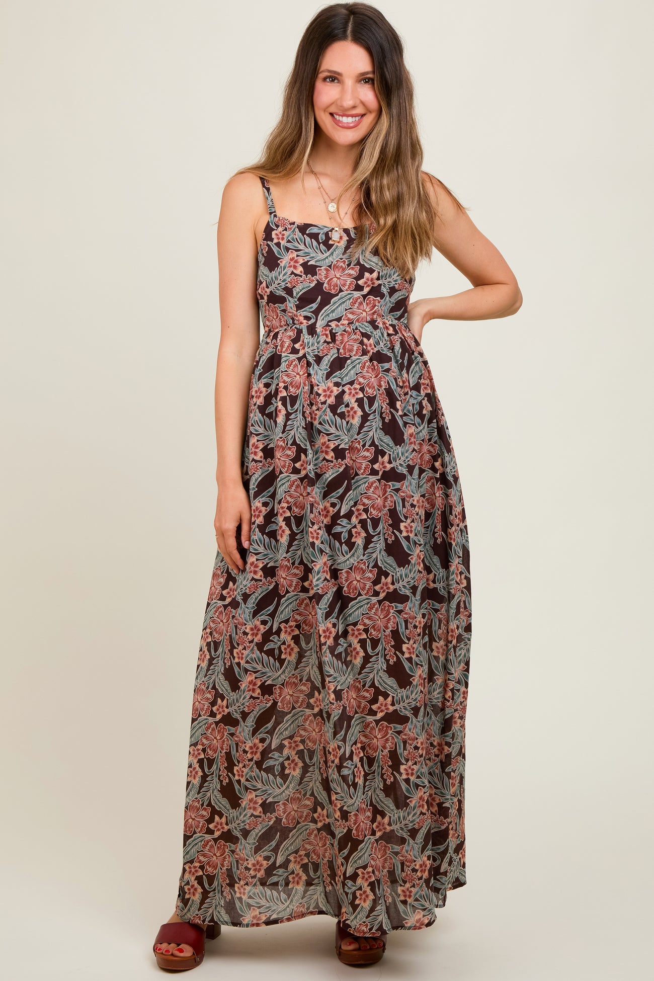 woman wearing a floral printed maternity maxi dress with adjustable straps and a flowing silhouette