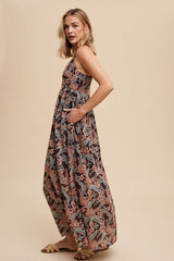 woman wearing a flowy black floral maxi dress with pockets and a fitted bodice, styled with sandals