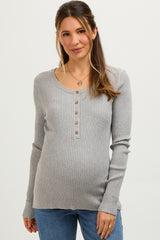 woman wearing a light grey ribbed maternity top with a henley neckline and buttons, highlighting her baby bump