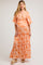 woman wearing a floral orange maternity maxi dress with a deep v-neckline and ruffled sleeves, showing her baby bump