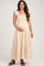 woman wearing a beige maternity maxi dress with ruffled straps and a smocked bodice, holding her baby bump