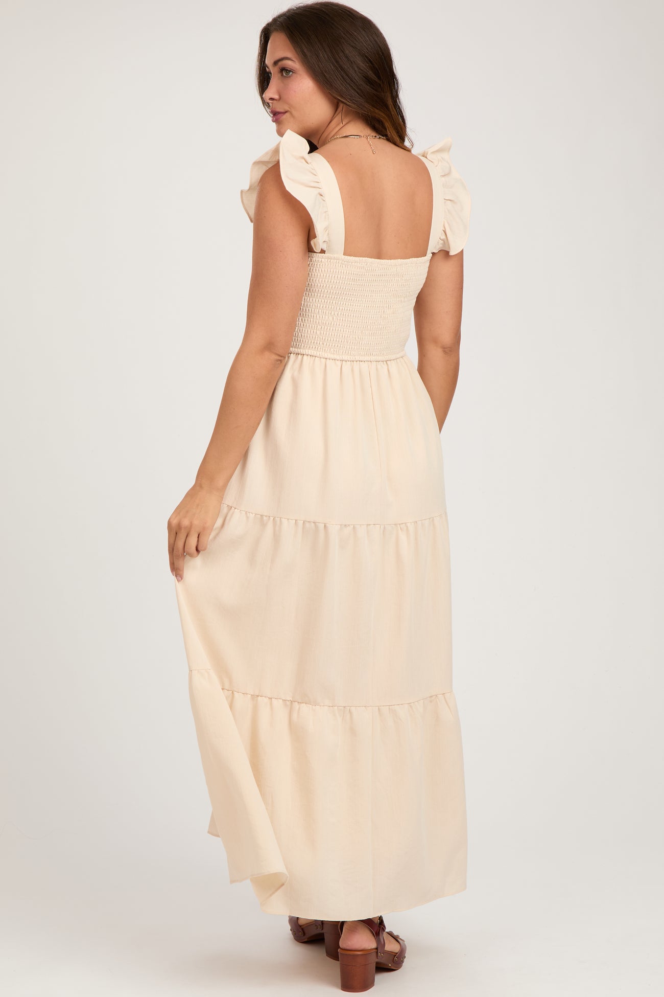 woman wearing a light beige maternity maxi dress with ruffled straps and a smocked bodice