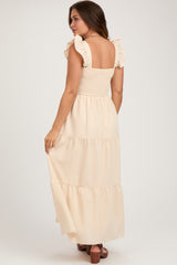 woman wearing a light beige maternity maxi dress with ruffled straps and a smocked bodice