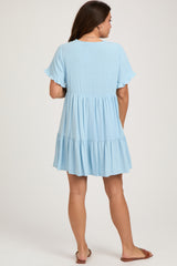 woman wearing a light blue maternity dress with short ruffled sleeves and a tiered hem, showcasing a baby bump