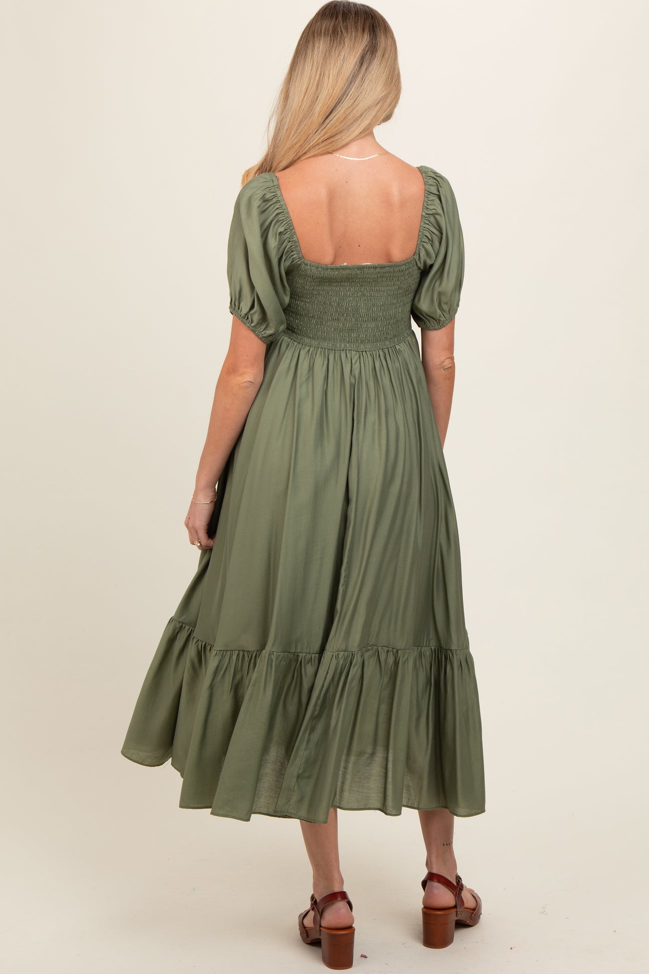 woman wearing a green maternity maxi dress with puff sleeves and a smocked bodice, showing her back