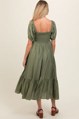 woman wearing a green maternity maxi dress with puff sleeves and a smocked bodice, showing her back