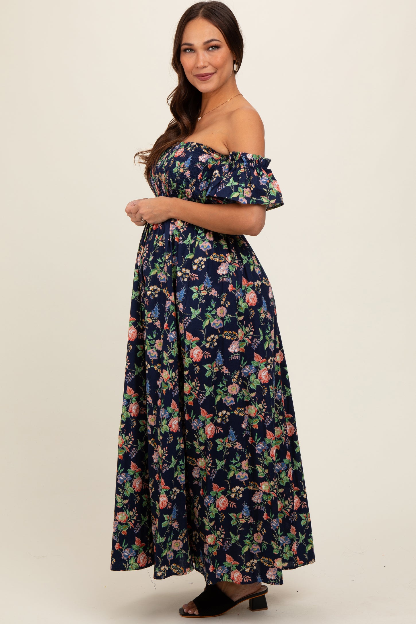 woman wearing a navy floral off-the-shoulder maxi dress with a visible baby bump