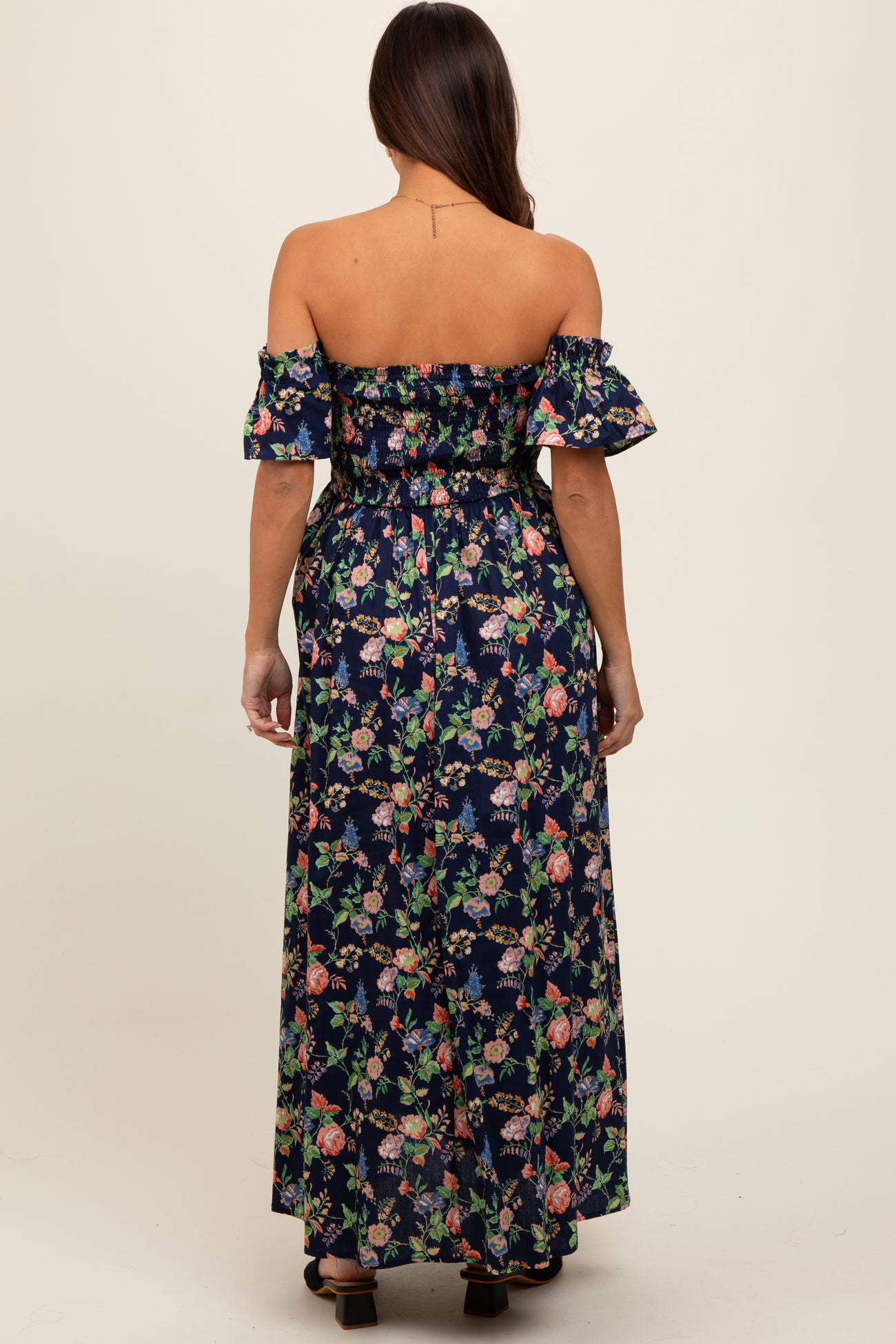 woman wearing a navy blue off-shoulder floral maternity maxi dress with wide sleeves and a fitted waist, showing her baby bump